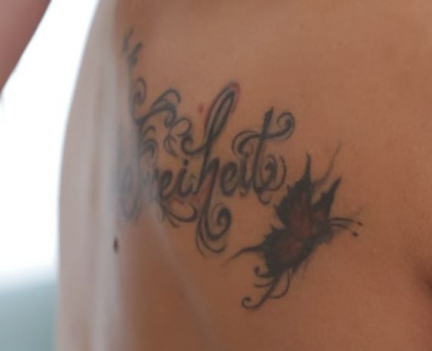 Text (Freiheit) with butterfly on right shoulder blade